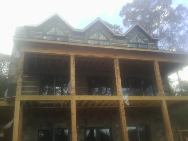 Dormers and porch framing on a large log home under construction — Roof Coating work by our crew in Corona